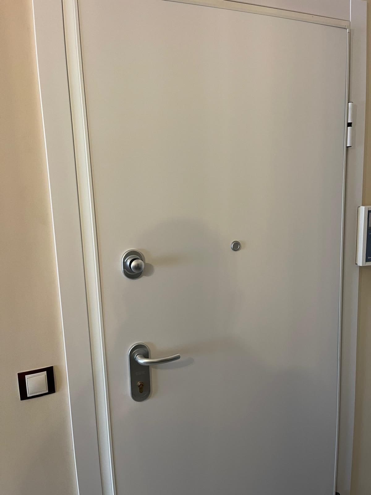 Puerta acorazada blanca con manilla y escudo de seguridad