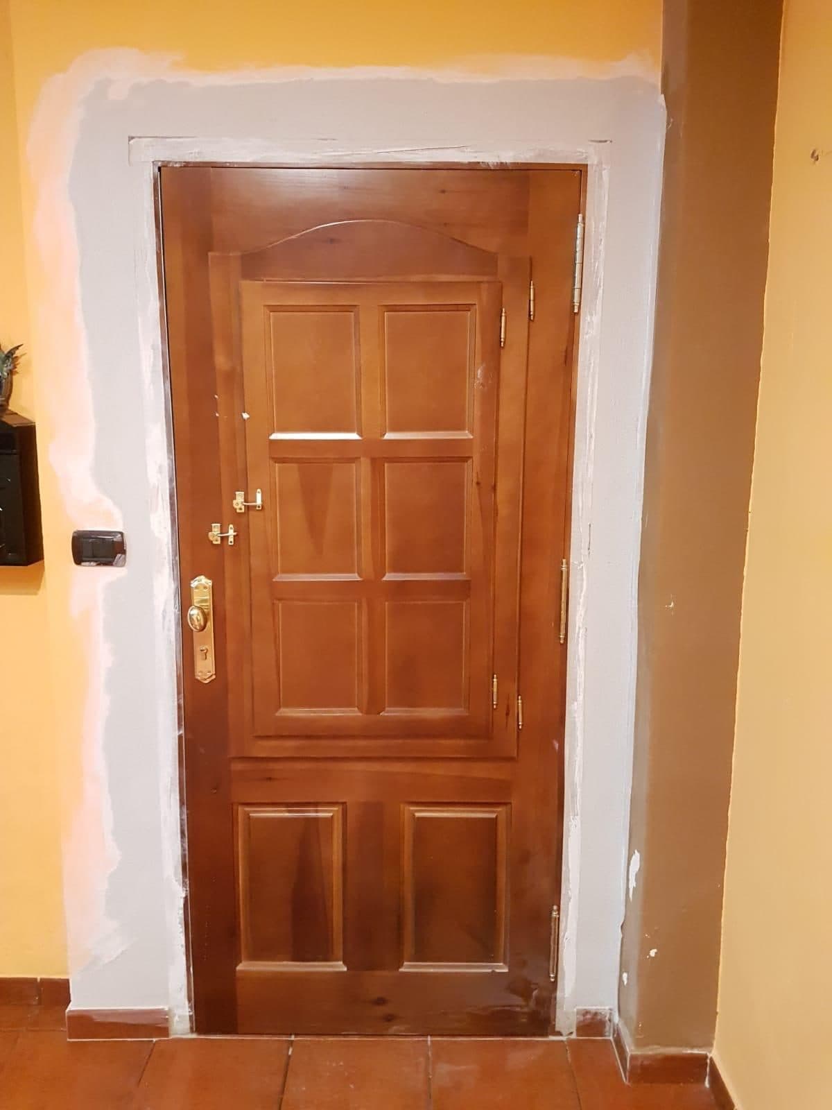 Puerta de entrada de madera de cuarterones con cerradura de seguridad de latón