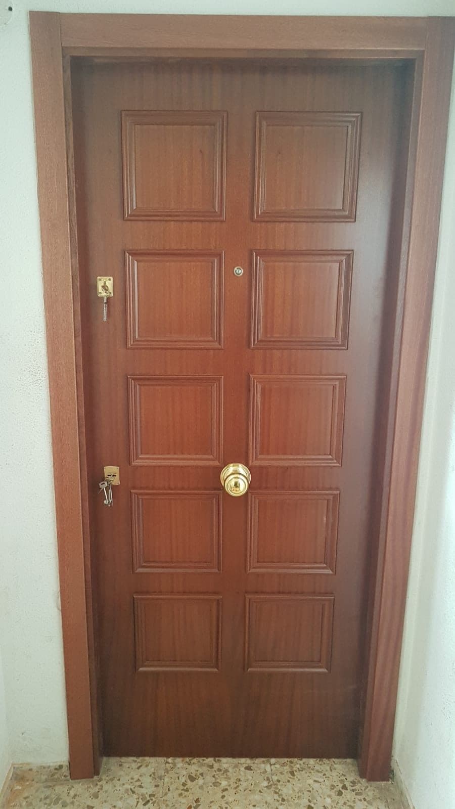 Puerta de entrada de madera con herrajes de latón