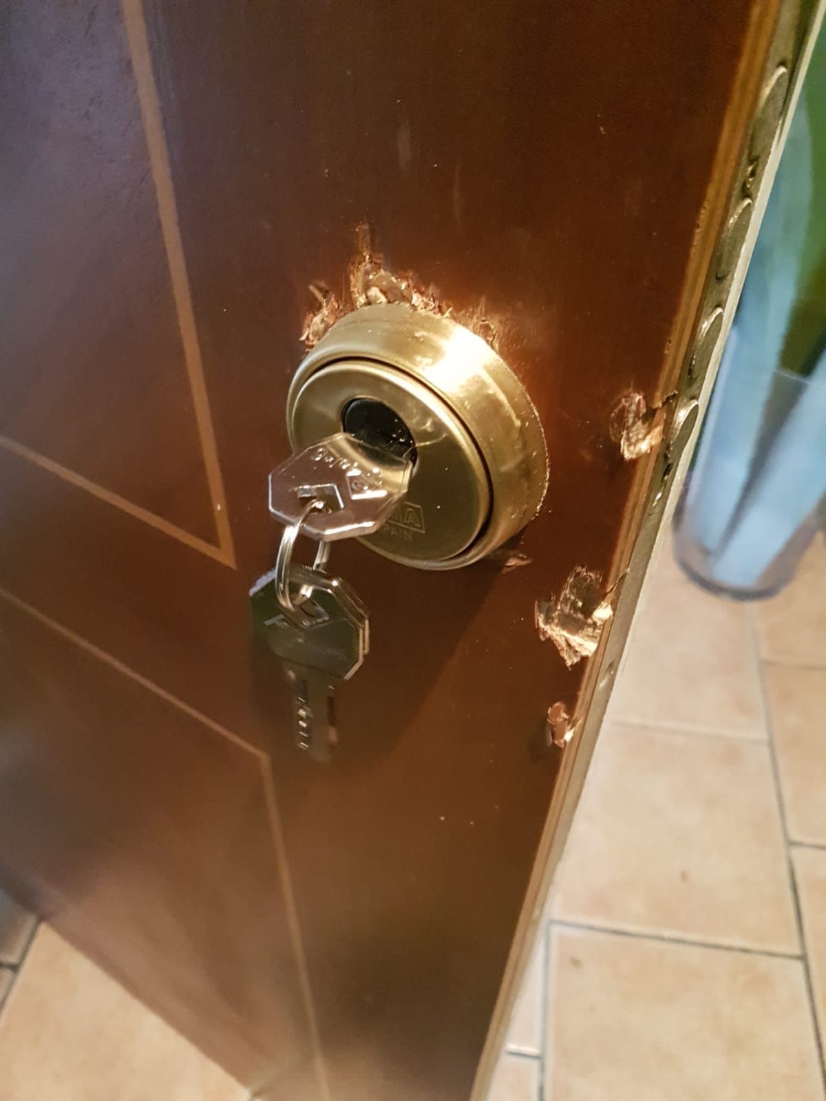 Escudo de seguridad de latón con la llave puesta en una puerta de madera